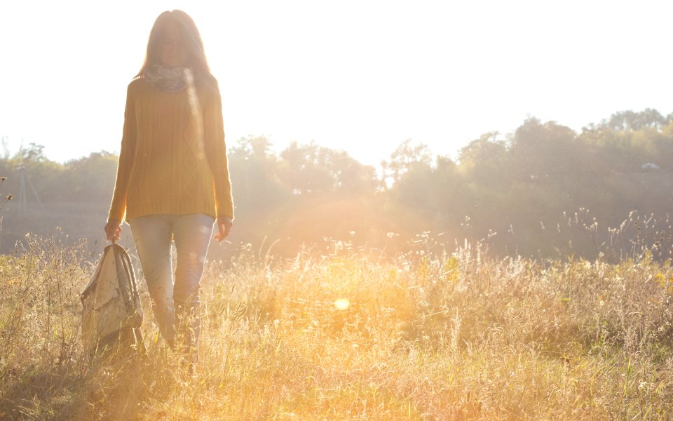 A woman walking through a golden, sunlit meadow