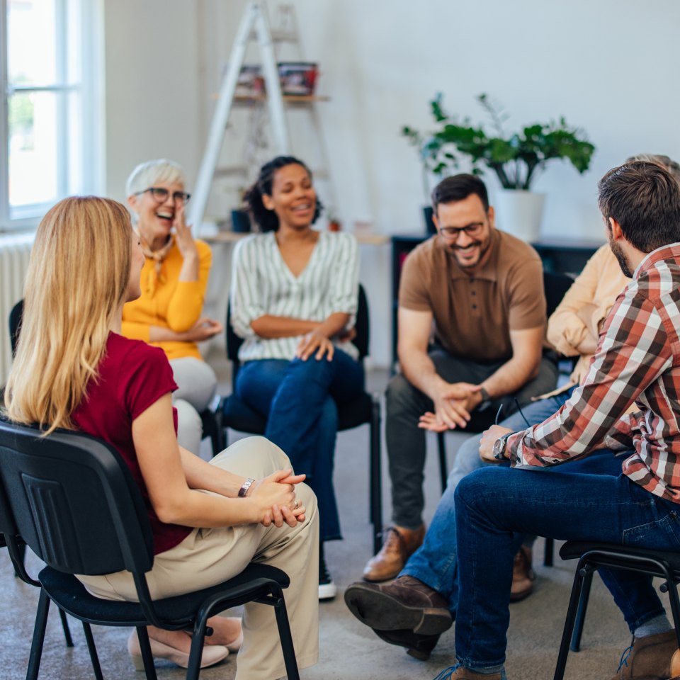 People sitting in a circle on chairs, talking with each other