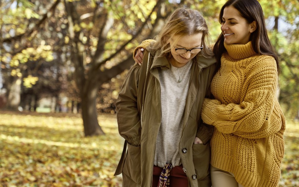 Two women walking arm in arm in an autumn park