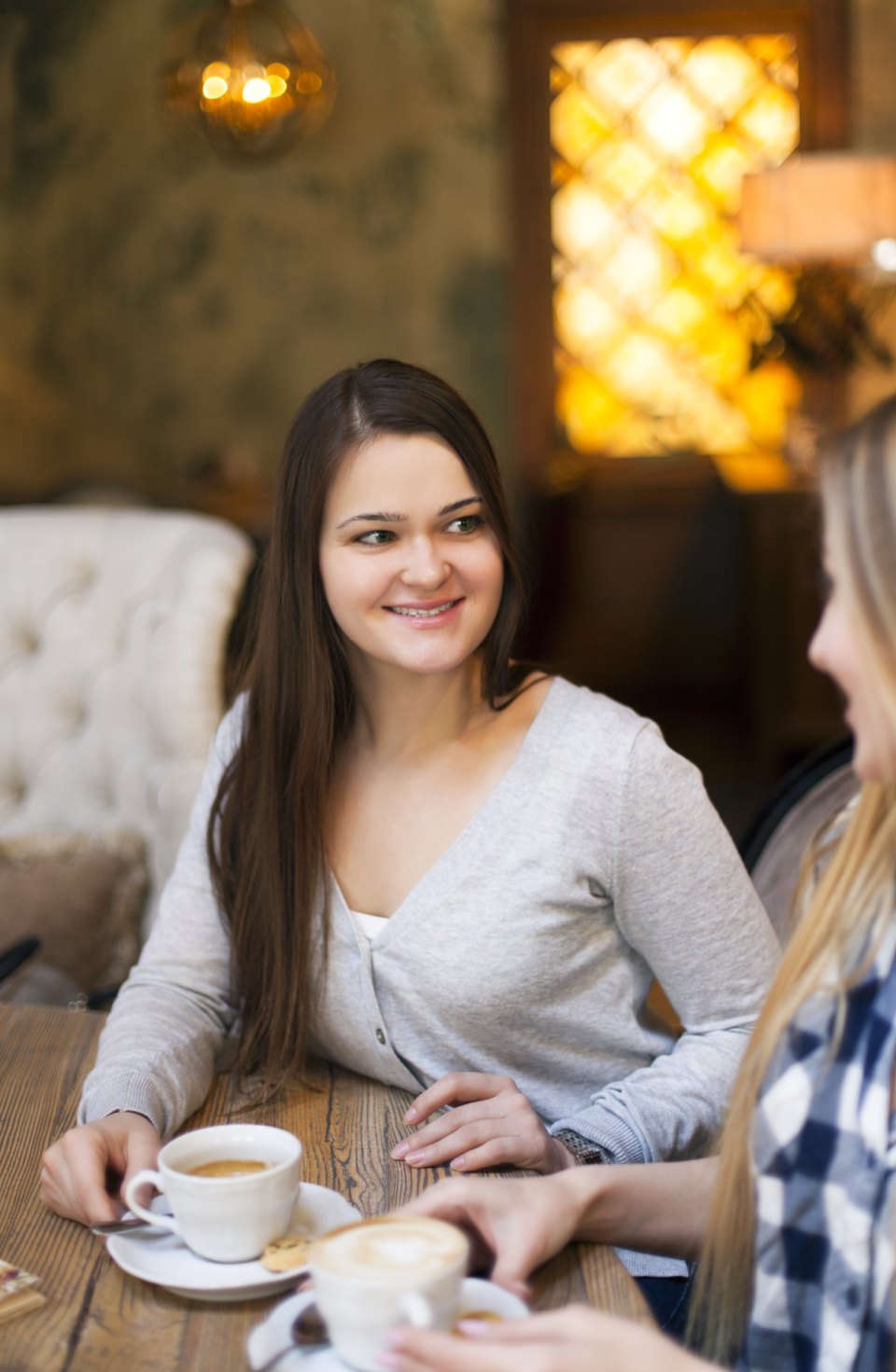 Smiling woman at a café table, her friends chatting beside her